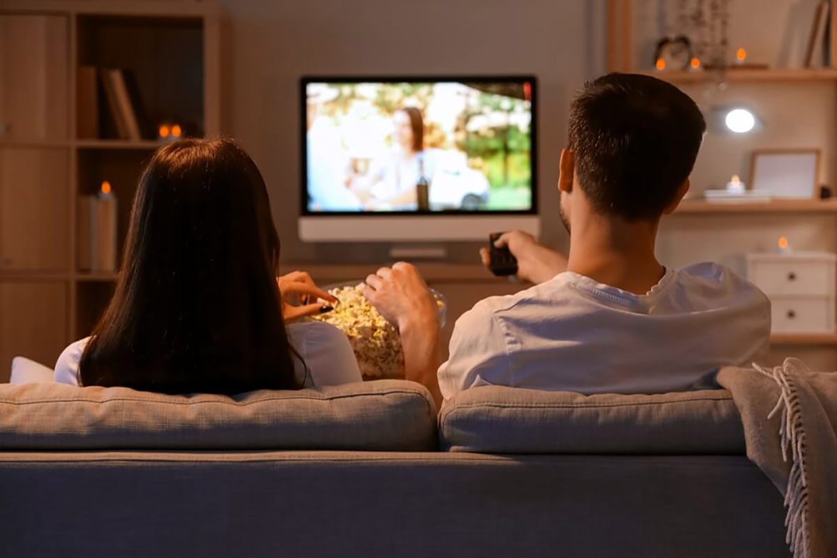 Pāris skatās televizoru uz dīvāna